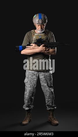 Ukrainian soldier with assault rifle on dark background Stock Photo