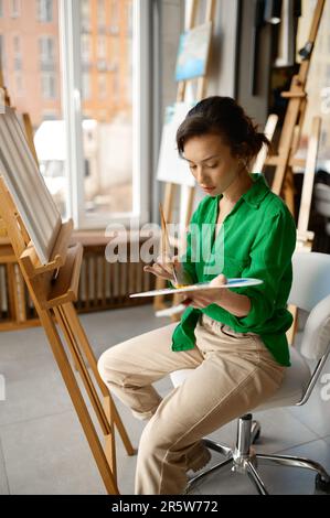 Woman painting brush on canvas at workshop during art lesson class Stock Photo