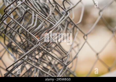 Close-up of a chain-link fence against a cloudy sky, protection against intrusion and restriction of freedom, selective focus Stock Photo