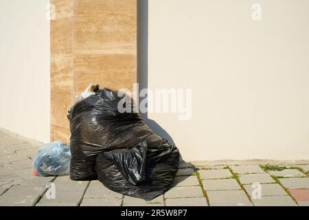 https://l450v.alamy.com/450v/2r5w8p7/pile-of-garbage-in-black-plastic-garbage-bags-on-the-sidewalk-by-the-road-in-a-big-city-space-for-text-garbage-from-pollution-waste-recycling-recy-2r5w8p7.jpg