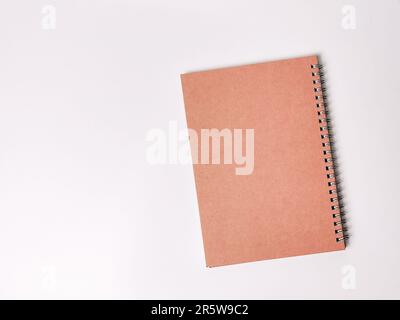 A brown spiral notebook lying flat on a white surface. Stock Photo