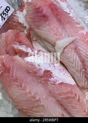 Fresh raw fish on ice with a price tag in the background Stock Photo