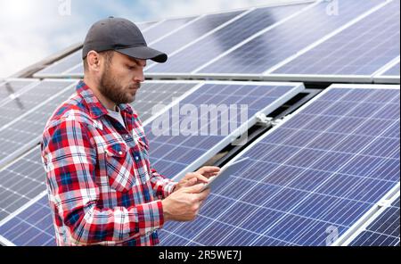 Field engineer performs diagnostics of solar energy station using wireless digital tablet. Stock Photo