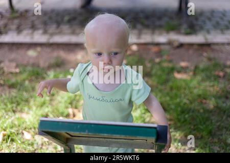 Cute little blonde baby boy standing near info desk in the park Stock Photo