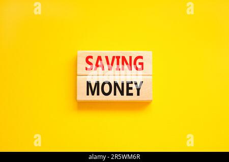 Saving money symbol. Concept words Saving money on wooden blocks on a beautiful yellow table yellow background. Business, support and saving money con Stock Photo