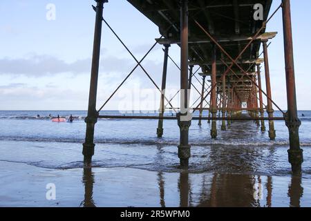 Saltburn Beach, North Yorkshire  2 January 2022 with walkers and paddle-boarders braving the chilly weather along the beach and pier Stock Photo