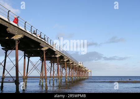 Saltburn Beach, North Yorkshire  2 January 2022 with walkers and paddle-boarders braving the chilly weather along the beach and pier Stock Photo