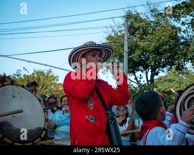 Barranquilla, Colombia - February 21 2023: Colombian Man Dressed in Red is Playing the Millet Flute While some Children Dance around him Stock Photo