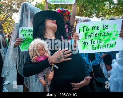 Barranquilla, Atlantico, Colombia - February 21 2023: Colombian Woman Dressed in Black with a Fake Pregnant Belly is Holding a Doll in the Last Carniv Stock Photo