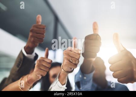 You should be proud of your achievements. Closeup shot of a group of businesspeople showing thumbs up in an office. Stock Photo