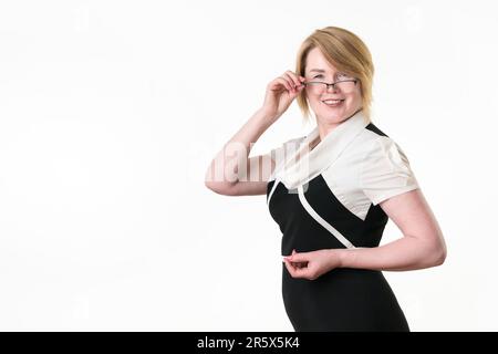 Portrait of feminine mature adult businesswoman with glasses looking at camera and lowering her glasses. Attractive business lady 49 years old optimis Stock Photo