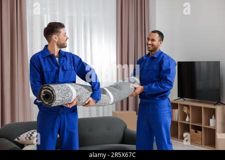 Male movers carrying carpet in new house Stock Photo