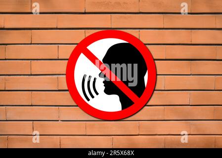 Quiet Please. Prohibition sign with human head image red brick wall Stock Photo