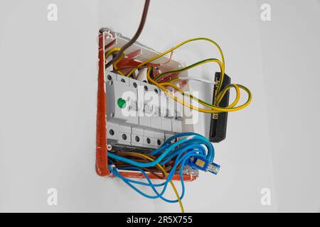 Switchboard with different cables on white wall. Installation of electrical wiring Stock Photo