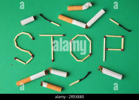 Word Stop made of matches and cigarette stubs on green background, flat lay. Stop smoking concept Stock Photo