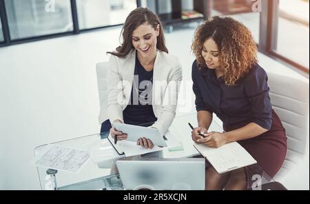 Always looking for ways to better our website. two businesswomen discussing something on a digital tablet. Stock Photo