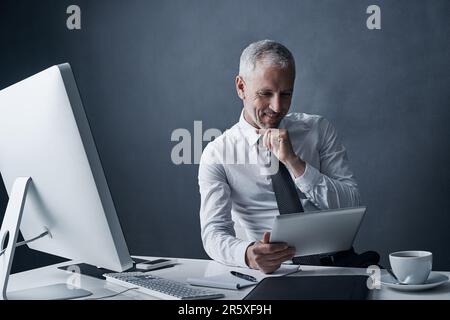 Thats impressive...a mature businessman working on his tablet. Stock Photo
