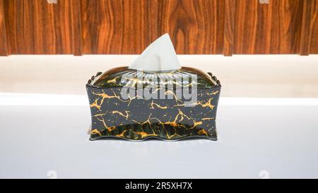 This tissue box holder features a sleek black design with golden patterns, making it a stylish addition to any room in your home. Stock Photo