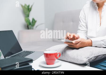 Social media day concept. Female freelancer starting working day early in living room for website with smartphone. Businesswoman working in home offic Stock Photo