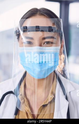 Im here to help stop the spread. Cropped portrait of an attractive young female doctor wearing a mask and face shield while standing in the hospital. Stock Photo