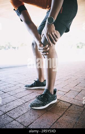 Fight through the bad days to get to the good. a man experiencing joint pain while working out against an urban background. Stock Photo
