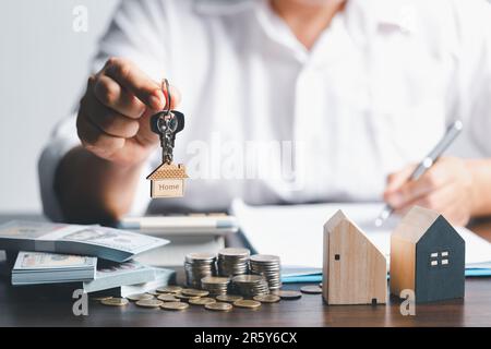 The house selling broker holds the keys and model house is given to the customers. house model with real estate agent professional with customer for s Stock Photo