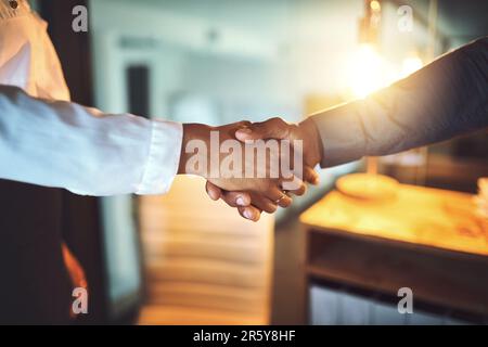 The day was done when they reached a new deal. Closeup shot of two unrecognizable businesspeople shaking hands in an office at night. Stock Photo