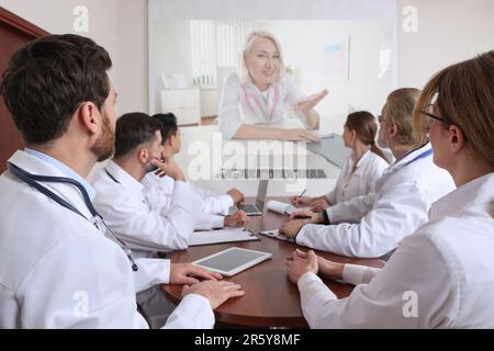 Lecture with online participant. Doctors in meeting room. Using projector for videoconference Stock Photo