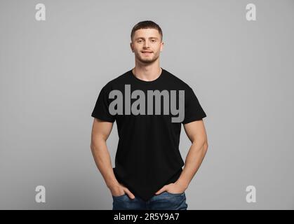 Man wearing black t-shirt on light grey background. Mockup for design Stock Photo