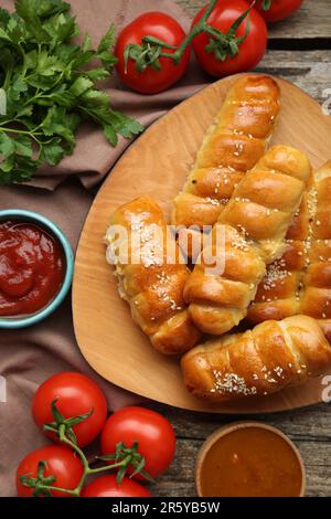 Delicious sausage rolls and ingredients on wooden table, flat lay Stock Photo