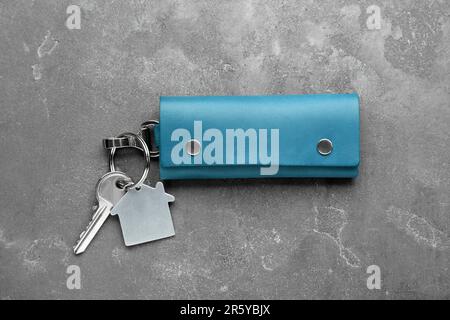 Leather case with key on grey textured table, top view. Stock Photo