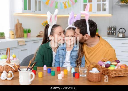 Happy family with Easter eggs at table in kitchen Stock Photo