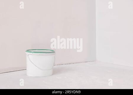 Bucket with paint in empty room, space for text Stock Photo