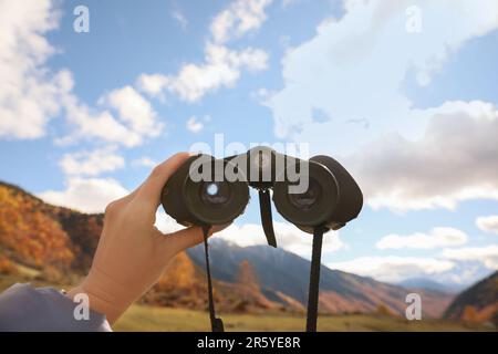 Boy holding binoculars in beautiful mountains, closeup Stock Photo