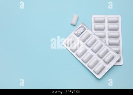 Blisters with chewing gums on light blue background, flat lay. Space for text Stock Photo