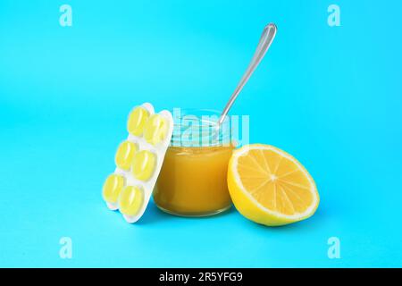 Blister with cough drops, fresh lemon and honey on light blue background Stock Photo