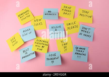 Paper notes with life-affirming phrases on pink background Stock Photo