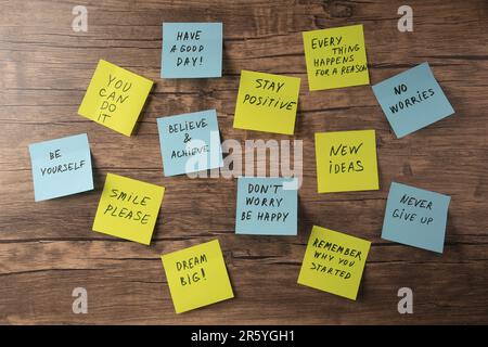Paper notes with life-affirming phrases on wooden table, flat lay Stock Photo
