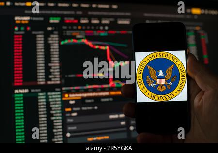 Kyiv, Ukraine - 06 June 2023: Man holds a smartphone with SEC logo against the background falling Bitcoin chart on Binance - crash. S.E.C. Accuses Stock Photo