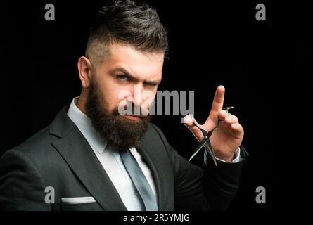 Facial care. bearded man in formal business suit. brutal male hipster cut hair with hairdressing scissors. confident businessman at barbershop. barber Stock Photo