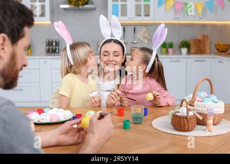 Happy family painting Easter eggs at table in kitchen Stock Photo