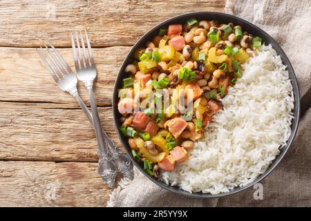 Hoppin John or Carolina peas and rice, is a black-eyed peas and rice with vegetables dish closeup on the plate on the wooden table. Horizontal top vie Stock Photo