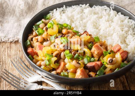 Hoppin John or Carolina peas and rice, is a black-eyed peas and rice with vegetables dish closeup on the plate on the wooden table. Horizontal Stock Photo