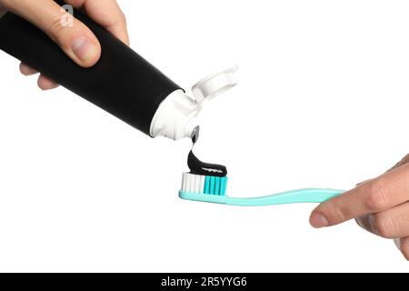 Woman applying charcoal toothpaste on brush against white background, closeup Stock Photo