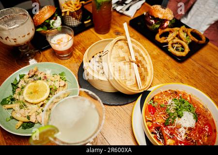 Overhead view of young man in casual clothing surrounded by food on table at restaurant Stock Photo