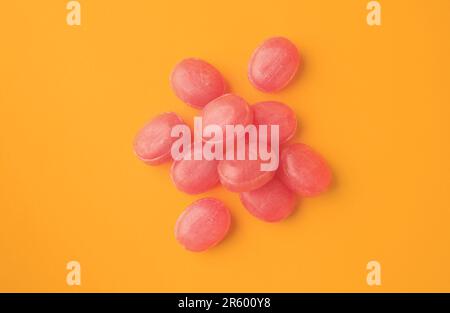 Many pink cough drops on orange background, flat lay Stock Photo