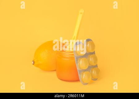 Blister with cough drops, fresh lemon and honey on orange background Stock Photo