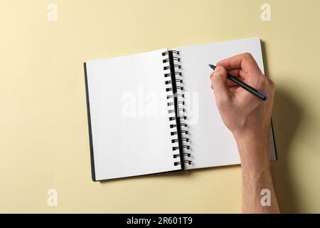 Man with pen and empty notepad on yellow background, top view Stock Photo