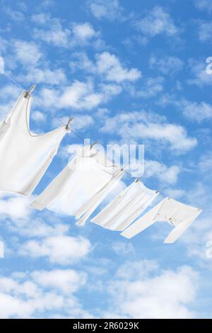 Different clothes drying on washing line against sky Stock Photo