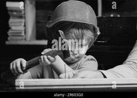 Funny little repairman with hammer. Kids construction worker. Child use a hammer to nail. Stock Photo